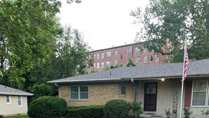 Una casa residencial con jardín delantero, acera y una bandera estadounidense.