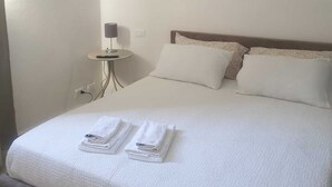 A neatly made bed with white linens and towels, a bedside table with a lamp, and a wall with circular decorations. - Detached house near the sea (Livorno)