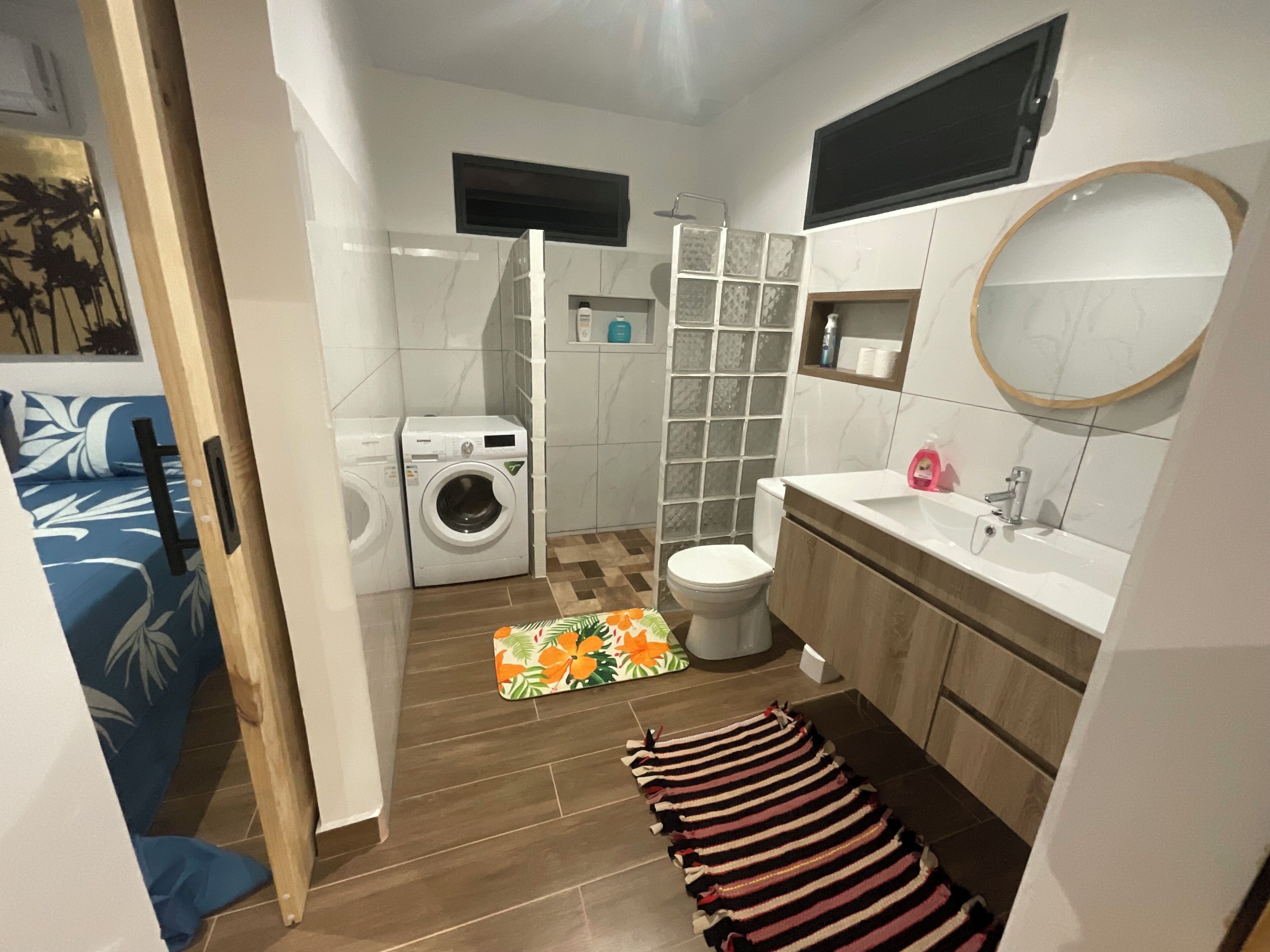 A compact bathroom with a washing machine, toilet, and sink.