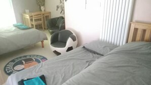 Een slaapkamer met twee bedden, een ronde stoel, een klein tafeltje en een wanddecoratie.