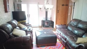 Een woonkamer met twee leren banken, een televisie, een open haard en een kleurrijk vloerkleed.