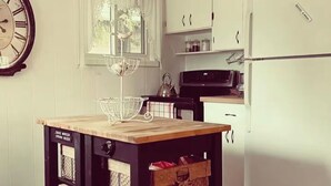 Een compacte keuken met witte kastjes, een houten tafel en een kroonluchter.