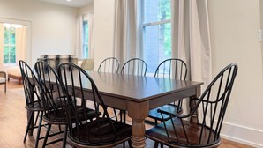 A dining area with a rectangular table and six chairs, a sofa, and a window with curtains. - Historical Charm-Saugatuck City-Sleeps 8 (Saugatuck)