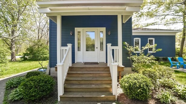 A two-story house with a front porch, white railings, and a set of stairs leading to the entrance. - Historical Charm-Saugatuck City-Sleeps 8 (Saugatuck)