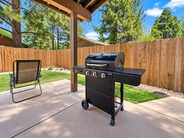 Una zona de barbacoa al aire libre con una silla y una valla de madera al fondo.