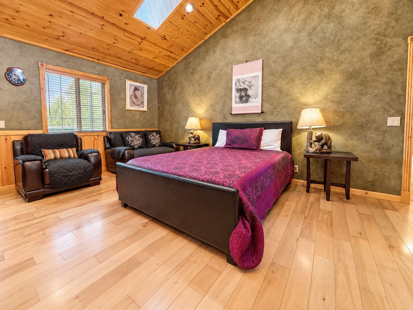 A bedroom with a large bed, a sofa, a desk, and a chair.