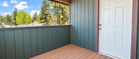 Un porche couvert avec un plancher en bois et une porte blanche.