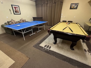 A pool table, a ping pong table, and a sofa in a room with a carpeted floor. - Casa Bella (Big Bear City)