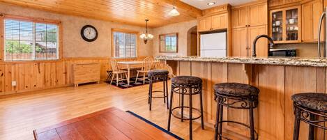 Une cuisine spacieuse avec des meubles en bois, un îlot central doté de tabourets de bar et une grande fenêtre qui laisse entrer la lumière naturelle.