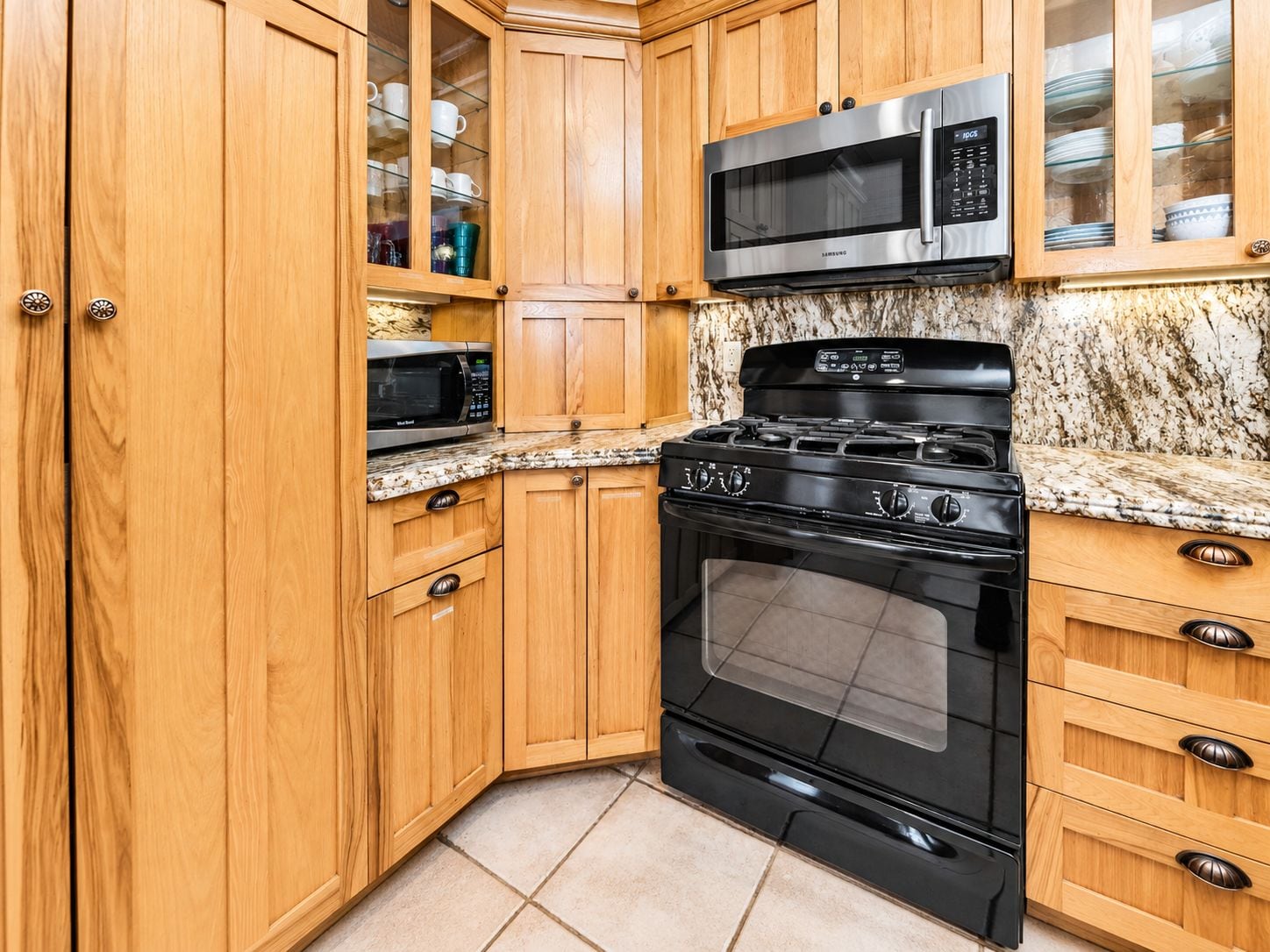 A kitchen with wooden cabinets, a stainless steel microwave, a gas stove, and a built-in oven.