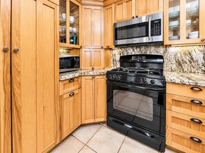 A kitchen with wooden cabinets, a stainless steel microwave, a gas stove, and a built-in oven. - Casa Bella (Big Bear City)