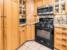 A kitchen with wooden cabinets, a stainless steel microwave, a gas stove, and a built-in oven.