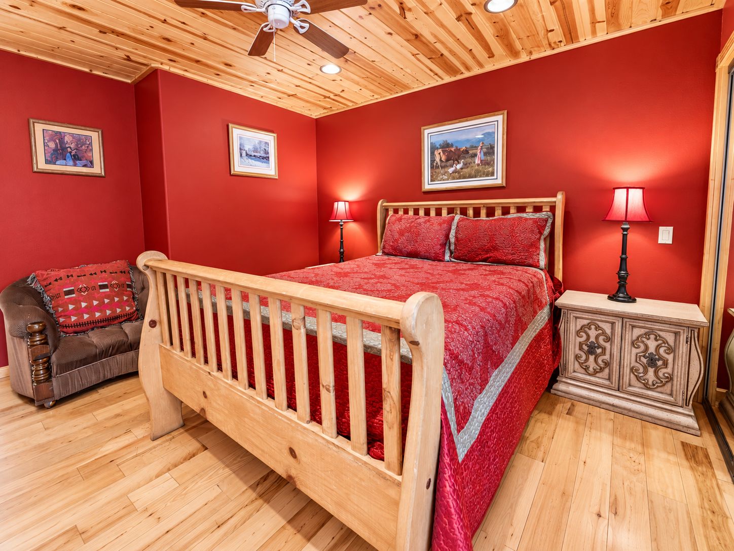 Un dormitorio con cama de madera, paredes rojas y ventilador de techo.