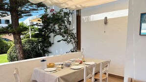 A dining area with a table set for four, surrounded by wicker chairs, under a white canopy. - Fabulous 170 m² terraced house in the heart of Fornells, with pool and garden (Fornells)