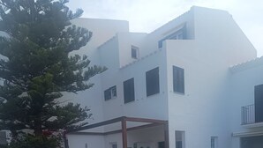 A modern white building with a swimming pool, a covered patio, and a well-maintained lawn. - Fabulous 170 m² terraced house in the heart of Fornells, with pool and garden (Fornells)