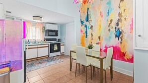 A modern kitchen with white cabinets, a microwave, and a dining area with a glass table and chairs. - Family Friendly Colorful Historic Uptown Home near Hospitals Ft Benning and CSU (Columbus)