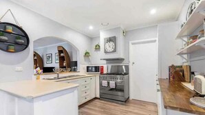 Een moderne keuken met witte kastjes, een roestvrijstalen fornuis en een magnetron.