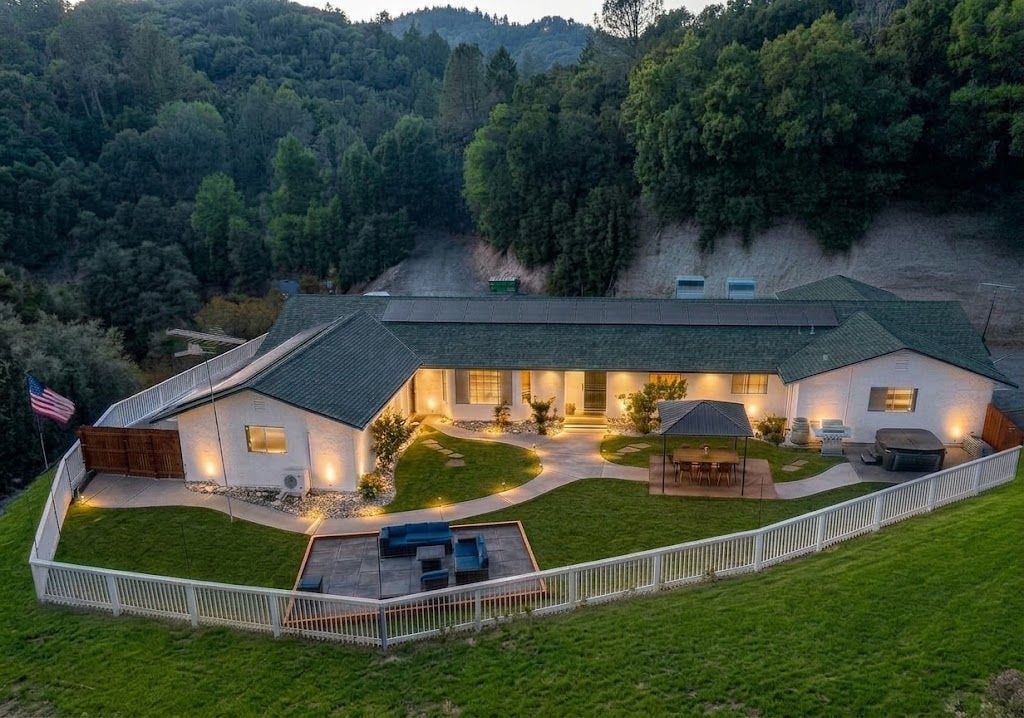 A two-story house with a covered patio, a flag, and a well-maintained lawn.