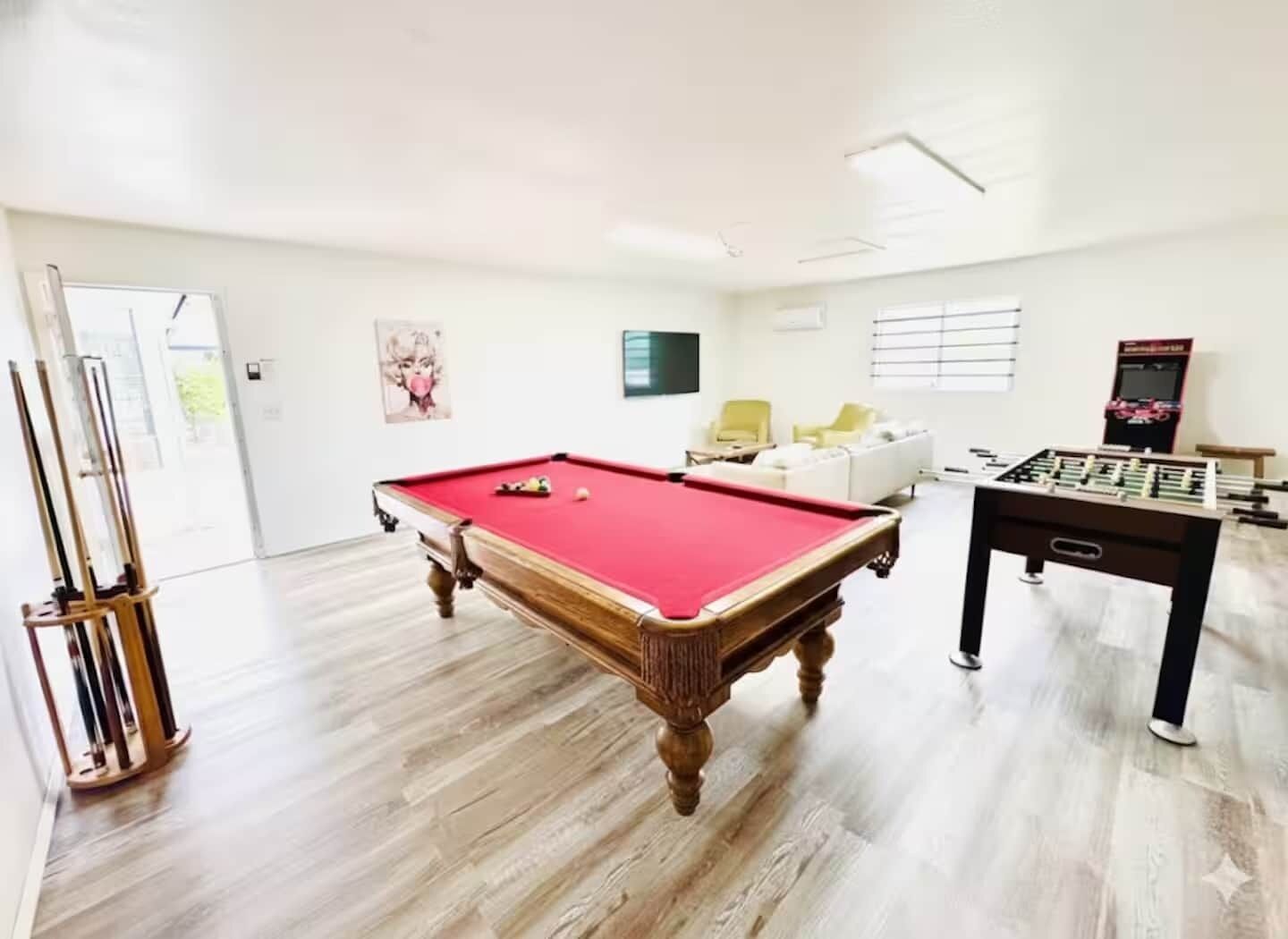 Ein geräumiger Raum mit Poolbillard-, Kicker- und Billardtischen.
