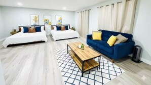 A modern living room with two beds, a blue sofa, and a coffee table.