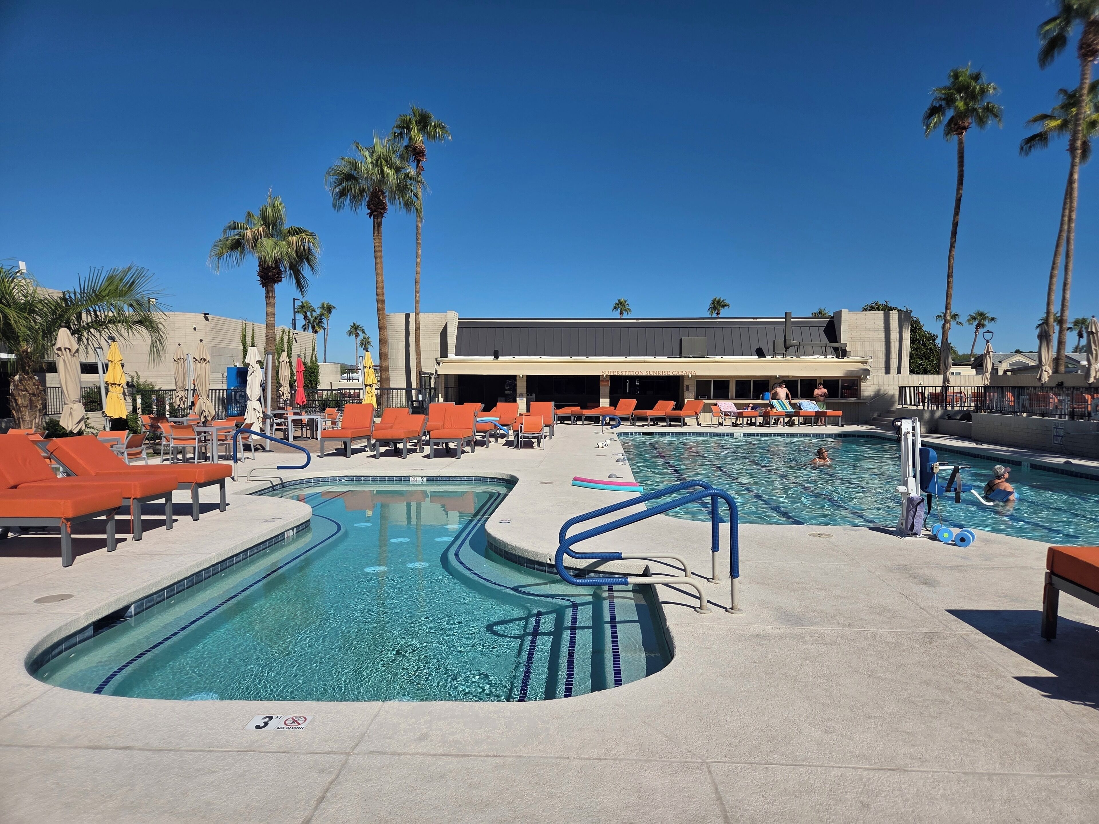A pool area with multiple lounge chairs and a pool with a lifeguard stand.
