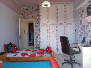 A bedroom with a bed, a desk, and a chair. There is a door leading to a bathroom.