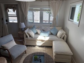 A cozy living room with a beige sofa, a grey armchair, and a wicker coffee table.