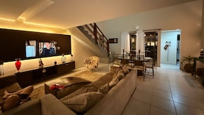 A modern living room with a sofa, TV, and a dining area with a table and chairs. - Cozy beach house in Porto de Galinhas, pet friendly. (Porto de Galinhas Ipojuca)