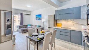 A modern apartment with a dining area, kitchen, and living space. - The Apateu (San Pawl il-Baħar)