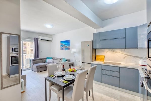 A modern apartment with a dining area, kitchen, and living space.