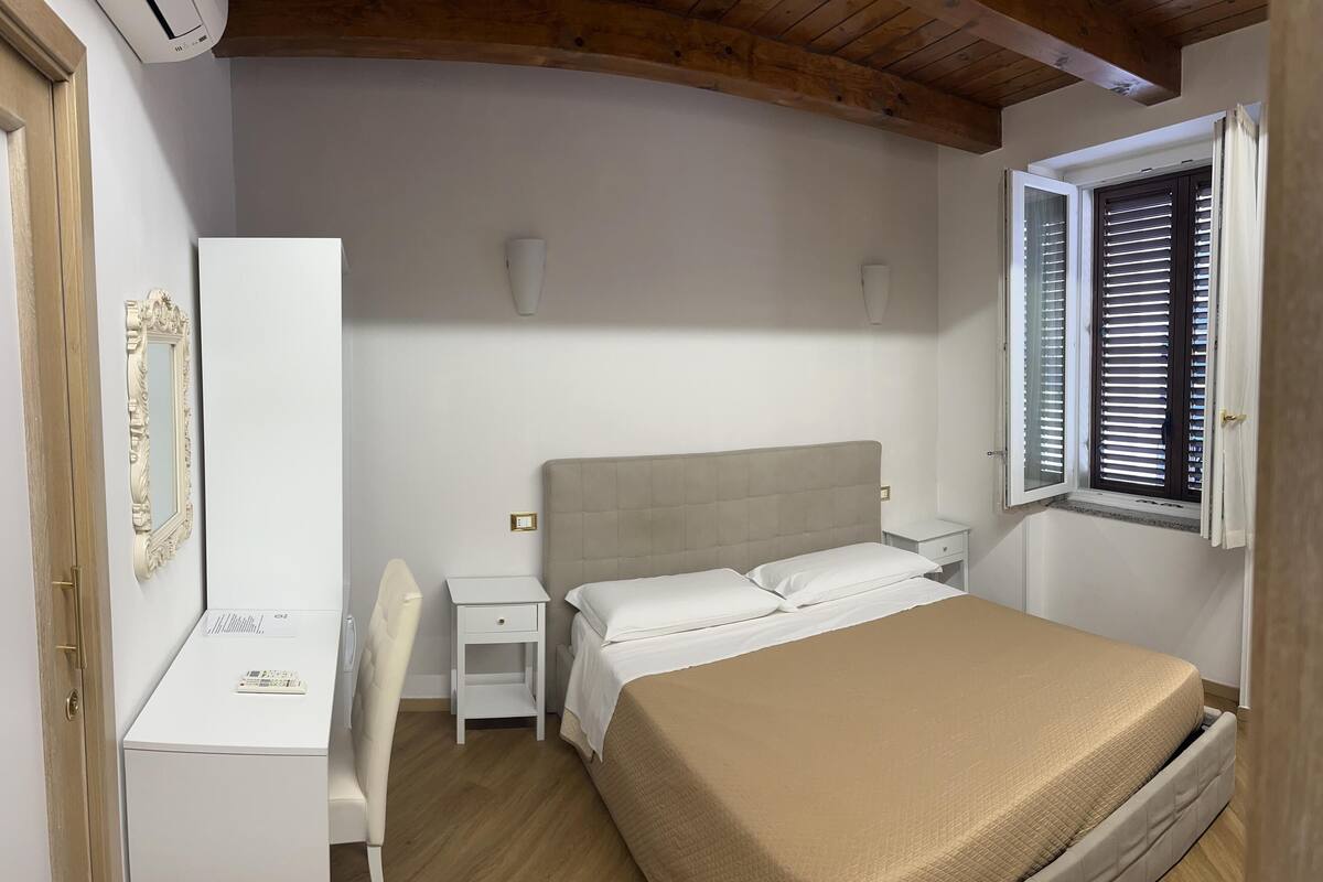 Un dormitorio con cama, mesita de noche y escritorio con silla.