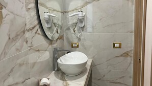 A modern bathroom with a large oval mirror, a white vessel sink, and a marble backsplash. - Fata34  (Reggio Calabria)