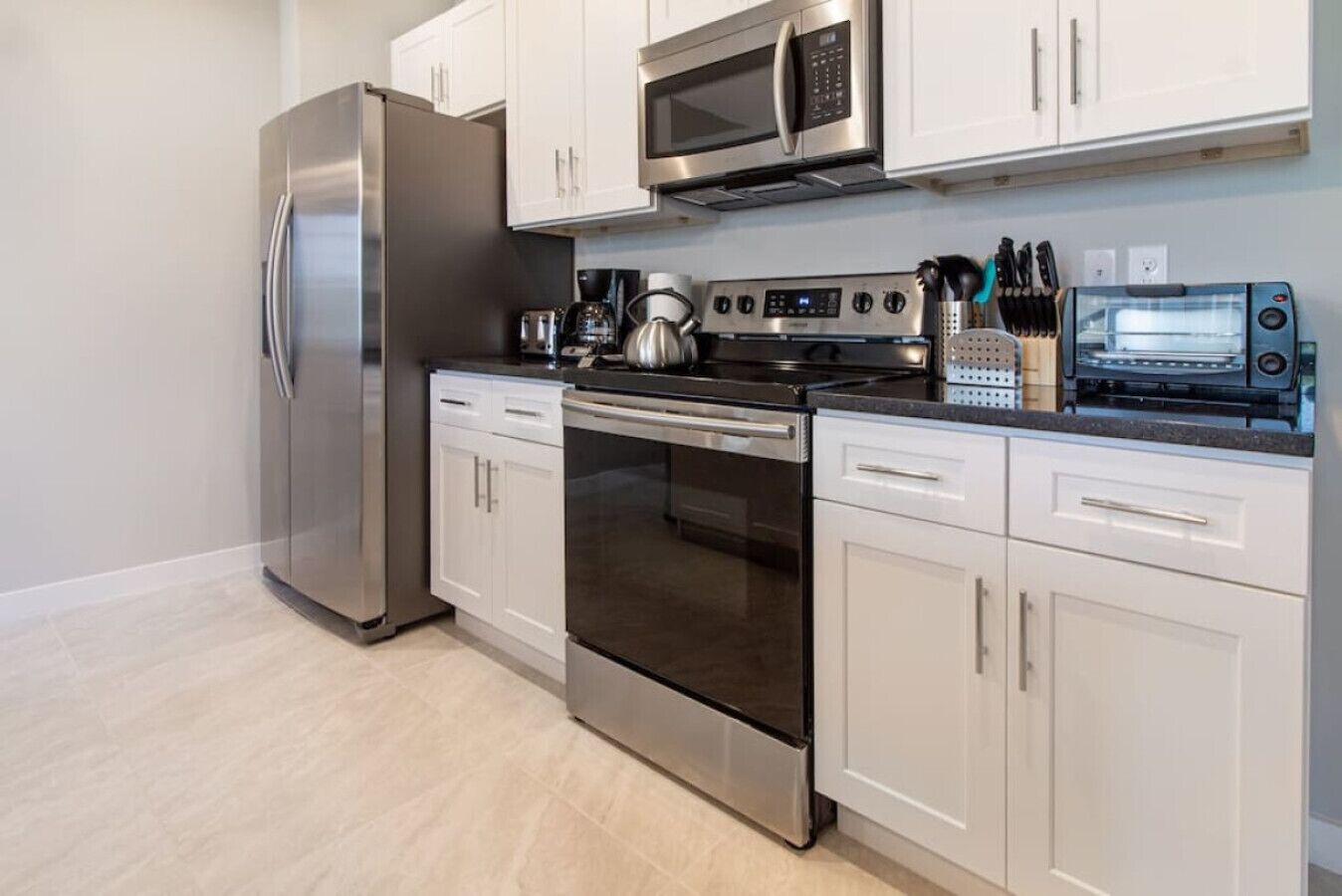 A modern kitchen with stainless steel appliances, white cabinetry, and a built-in oven.