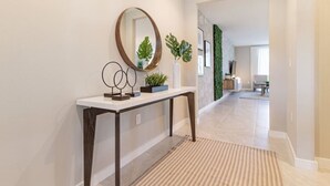 Un pasillo con una consola blanca, un espejo y elementos decorativos.