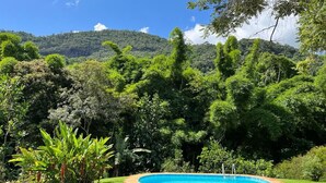 A swimming pool surrounded by lush greenery and a hill in the background. - Country House with Pool and Cinematic View in Luxury Condominium (Pedro do Rio)