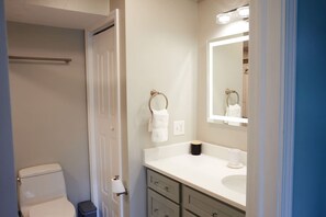 A bathroom with a toilet, a sink, a mirror, and a towel rack.