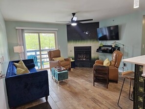 Una sala de estar con un sofá azul, un sillón de cuero marrón, una mesa de centro de madera y una chimenea.