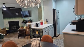 A modern kitchen with a central island, a dining area with a round table, and a living room with a fireplace.
