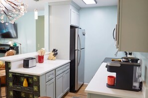 Eine moderne Küche mit Kühlschrank, Kaffeemaschine und Toaster auf der Arbeitsfläche.