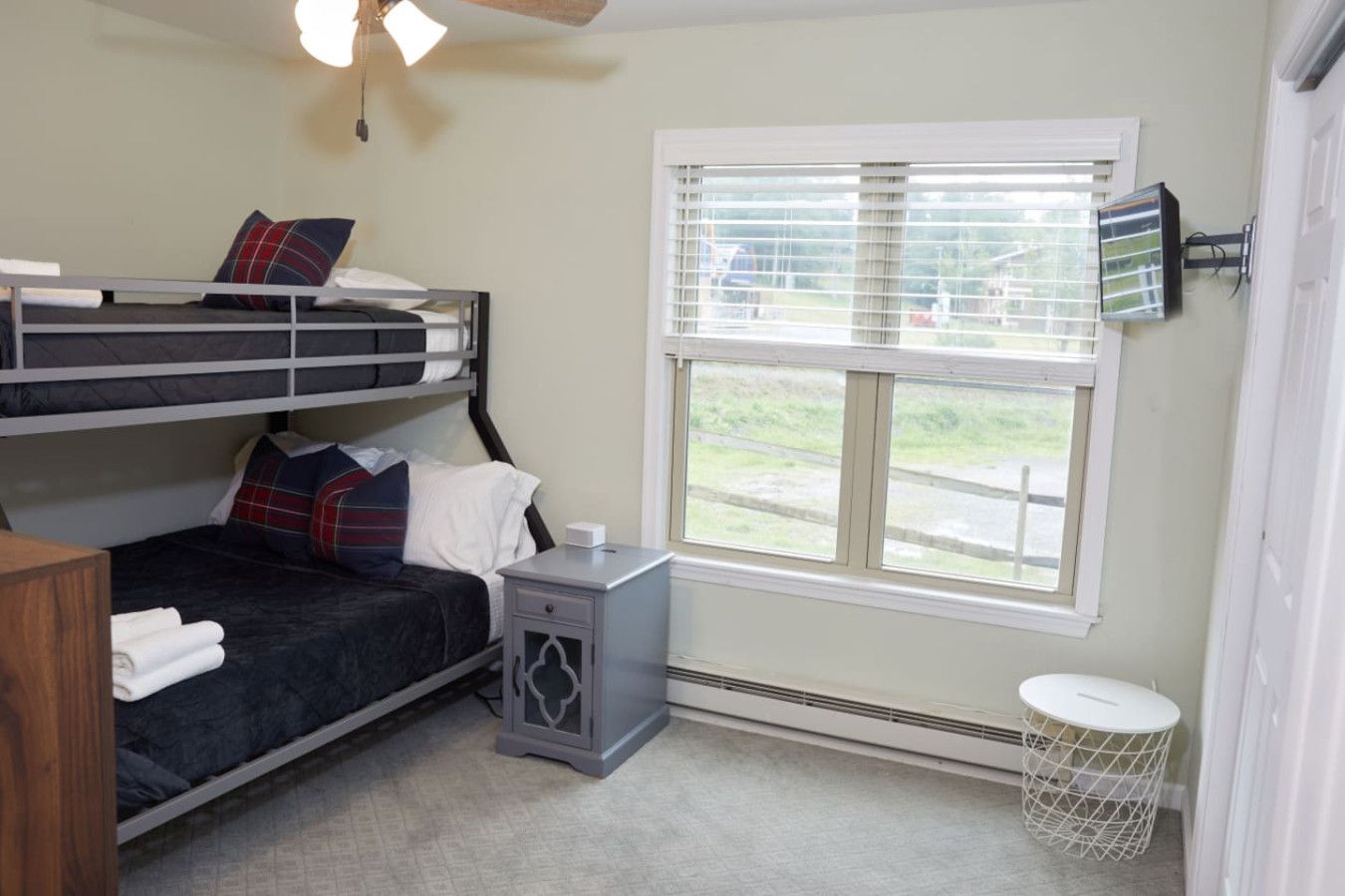 A bunk bed room with a window, a small table, and a radiator.