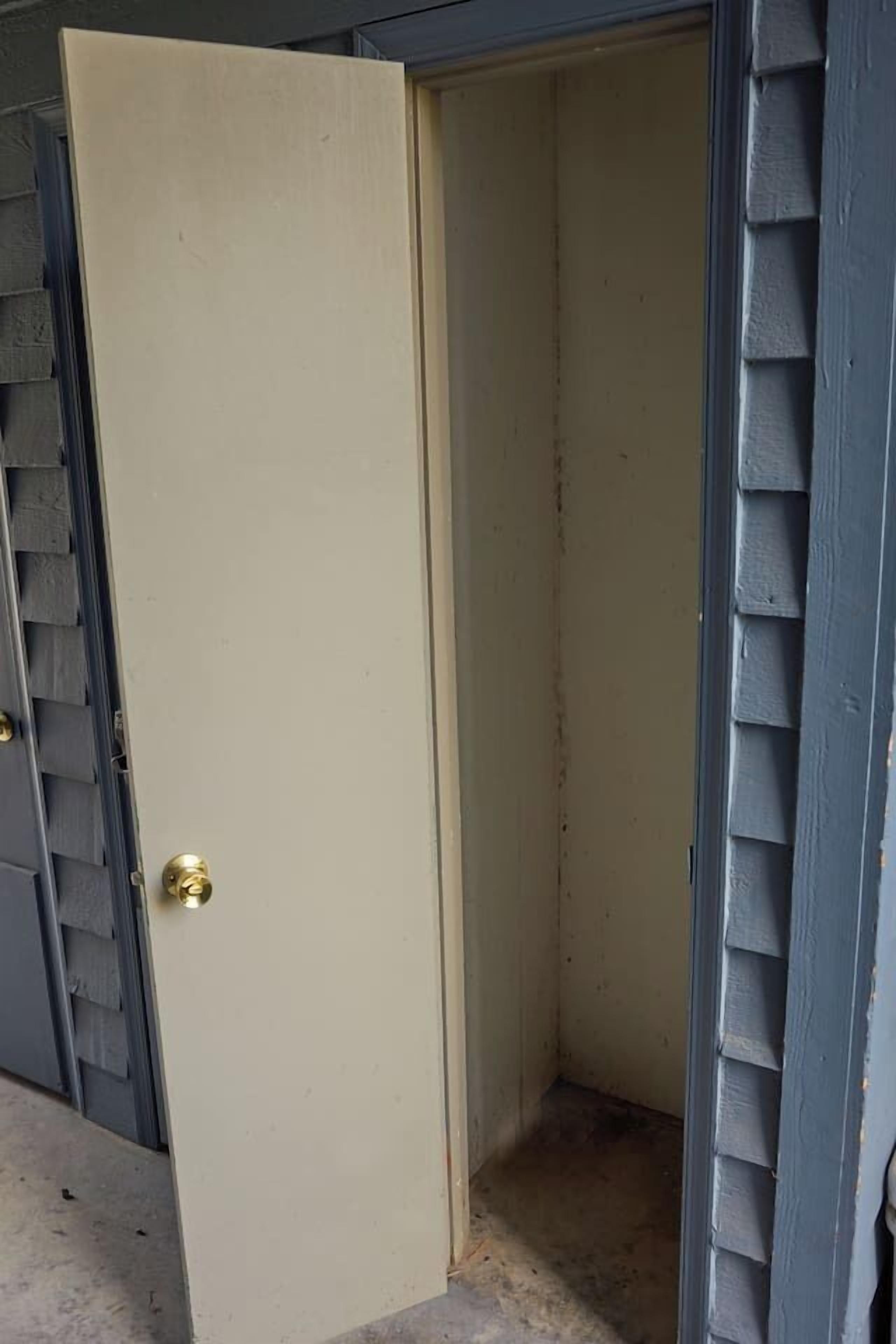 A closed door with a brass doorknob, a small step leading up to it, and a grey exterior wall with siding.