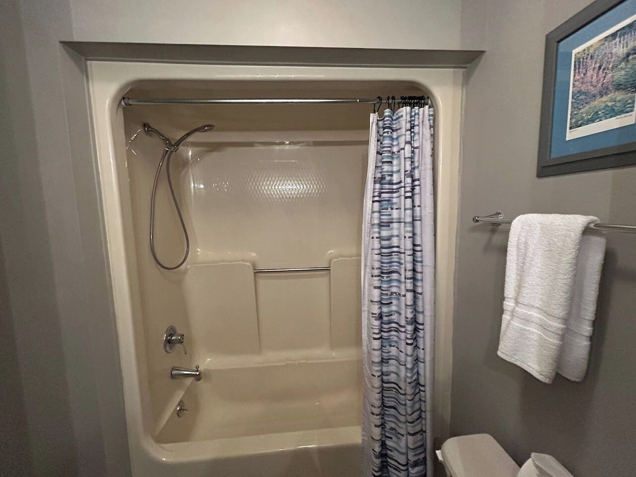 A bathroom with a bathtub, shower, and a towel rack.