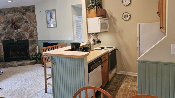 A compact kitchen with a stone fireplace, a bar area, and a dining space.