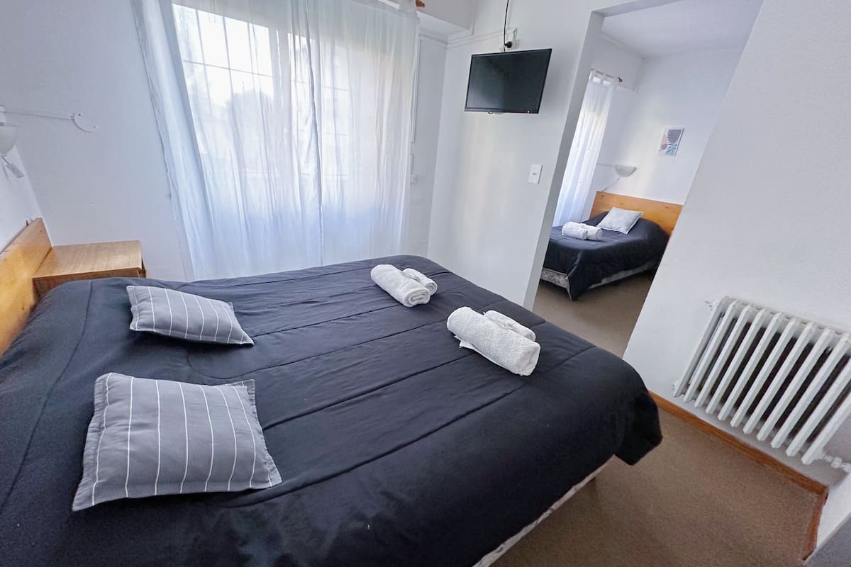Une chambre d’hôtel avec un grand lit, deux oreillers, un téléviseur à écran plat et un radiateur.