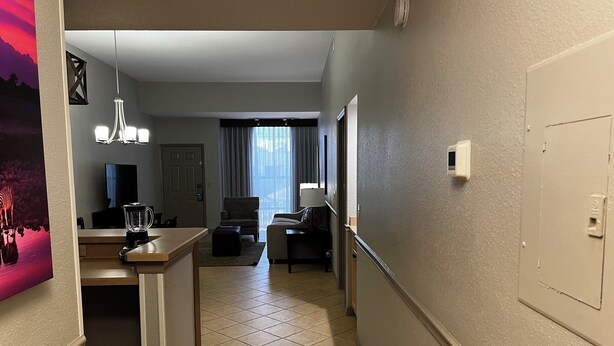 A hallway leading to a living area with a kitchen, a dining area, and a view of the outdoors. - Family Vacation Getaway (Kissimmee)
