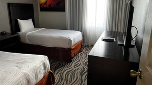A hotel room with two beds, a desk with a TV, a painting of giraffes, and a zebra-patterned carpet. - Family Vacation Getaway (Kissimmee)
