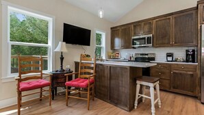 Una cocina con armarios de madera, microondas, cafetera y televisor.
