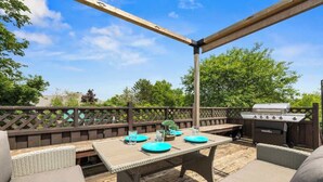 An outdoor patio with a wooden table, wicker furniture, and a barbecue grill. - Family Retreat  – King Bed, Jacuzzi & Big Backyard (Charlottetown)