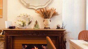 A fireplace with a fire, a mirror above it, and various decorative items on the mantel. - London Central 4Bed House with Garden (London)
