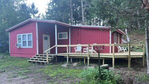 A red cabin with a wooden deck, a small porch, and a sign indicating 'AU TRAIN TWP N 7118'. - Cozy cabin with WiFi in charming Au Train, Completely remodeled as of June 2025 (Au Train)